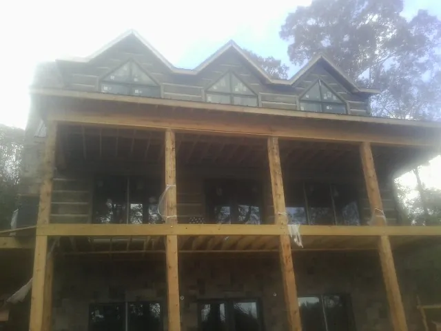 Dormers and porch framing on a large log home under construction — Roof Coating work by our crew in Cottage Grove